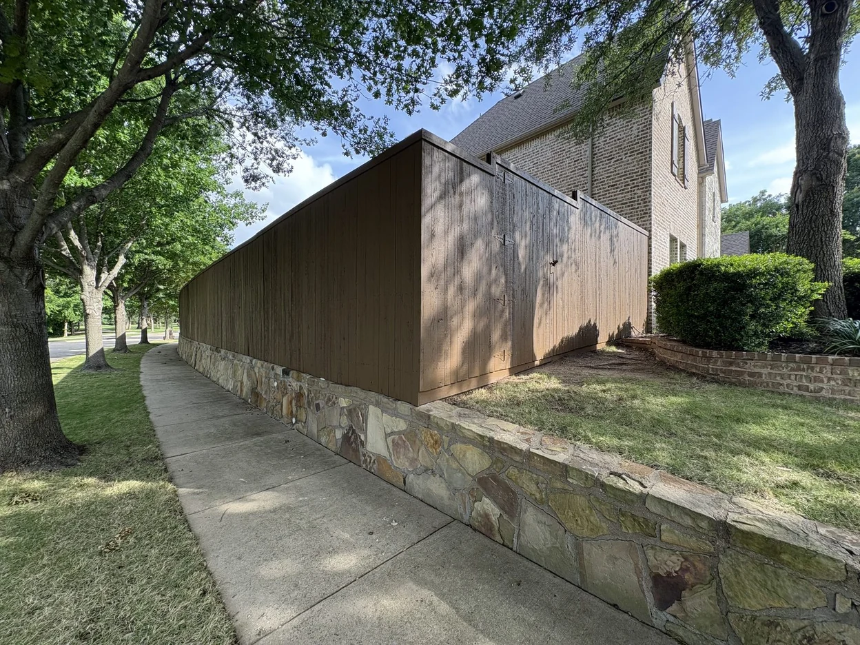 Privacy fence stained rich brown atop a stone wall by PG Painting